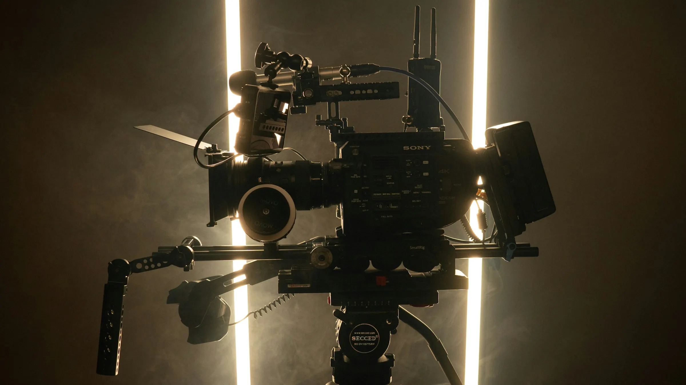 A cinema camera on set, lit by two light tubes in the dark