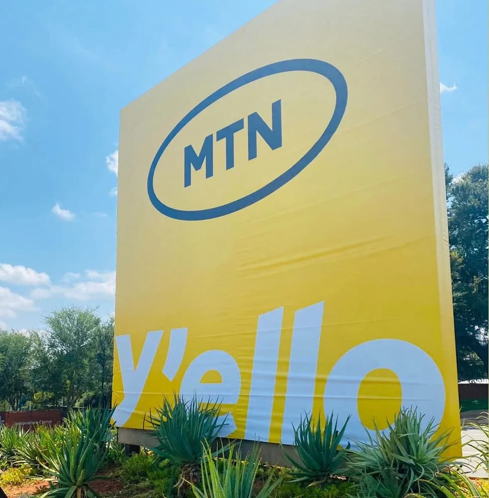A yellow MTN billboard reading y'ello against a blue sky