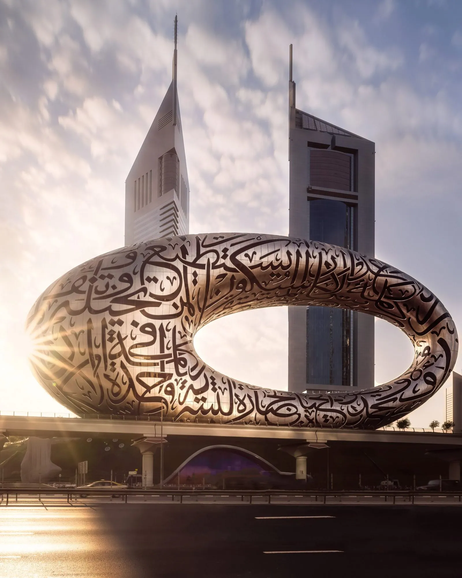 The Museum of the Future ring in Dubai at sunrise, Emirates Towers behind it